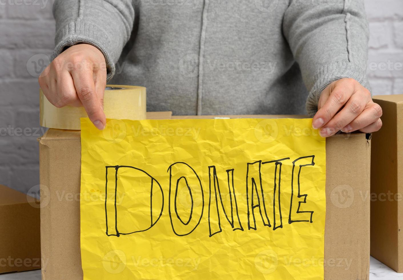 woman in a gray sweater holds a crumpled yellow sheet of paper with the inscription photo