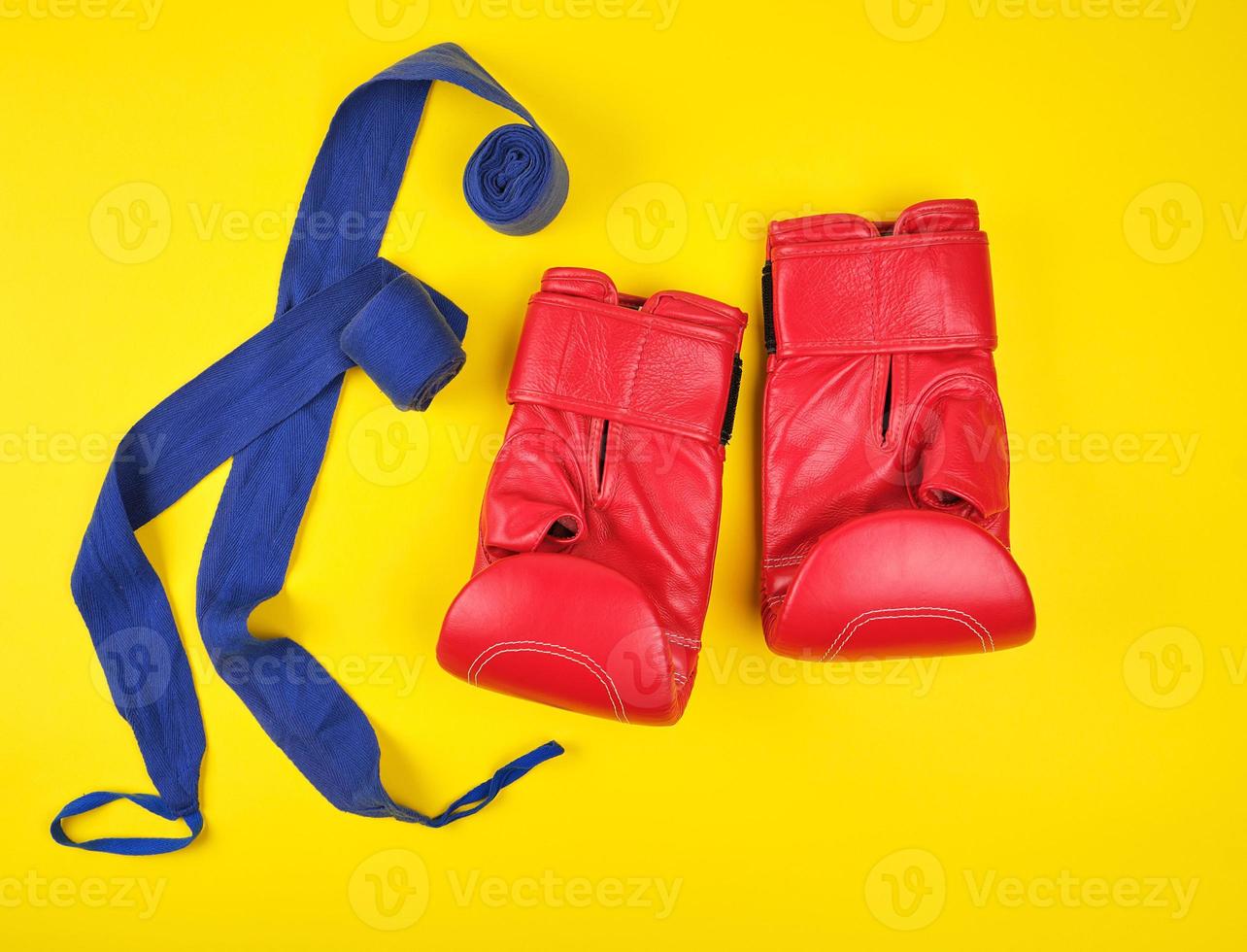 par de guantes de boxeo de cuero rojo y vendaje textil azul foto