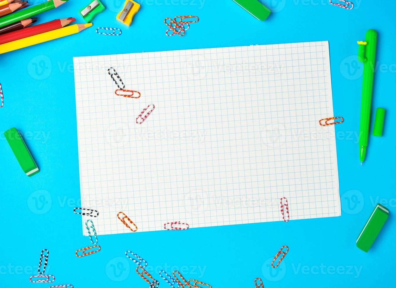 white squared paper from notebooks, wooden colored pencils, paper clips photo
