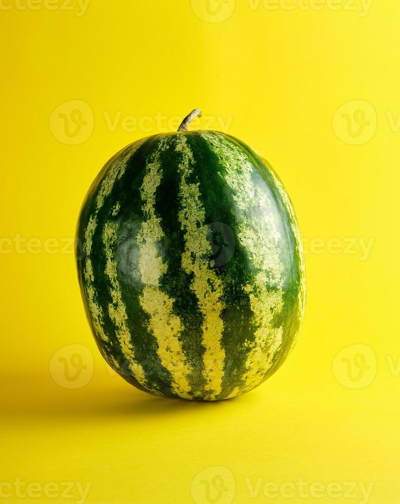big green striped whole watermelon on a yellow background photo