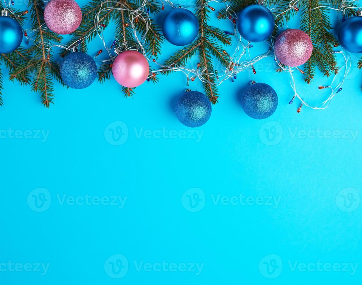 burning multi-colored light bulbs on a garland with a white cable and green twigs of needles photo