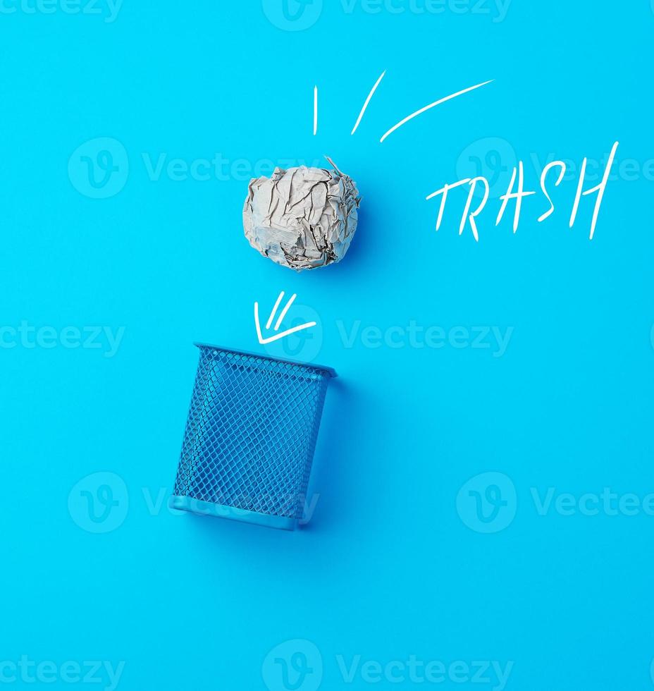 ball of crumpled gray paper and metal blue wastebasket photo