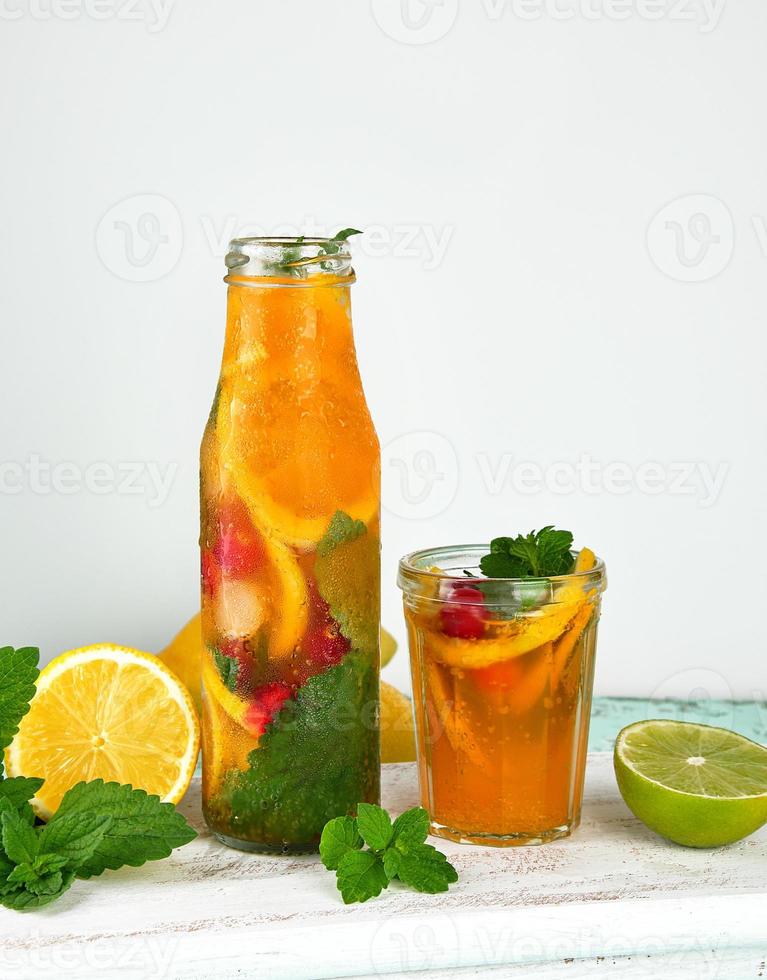 summer refreshing drink lemonade with lemons, cranberry, mint leaves, lime in a glass bottle photo