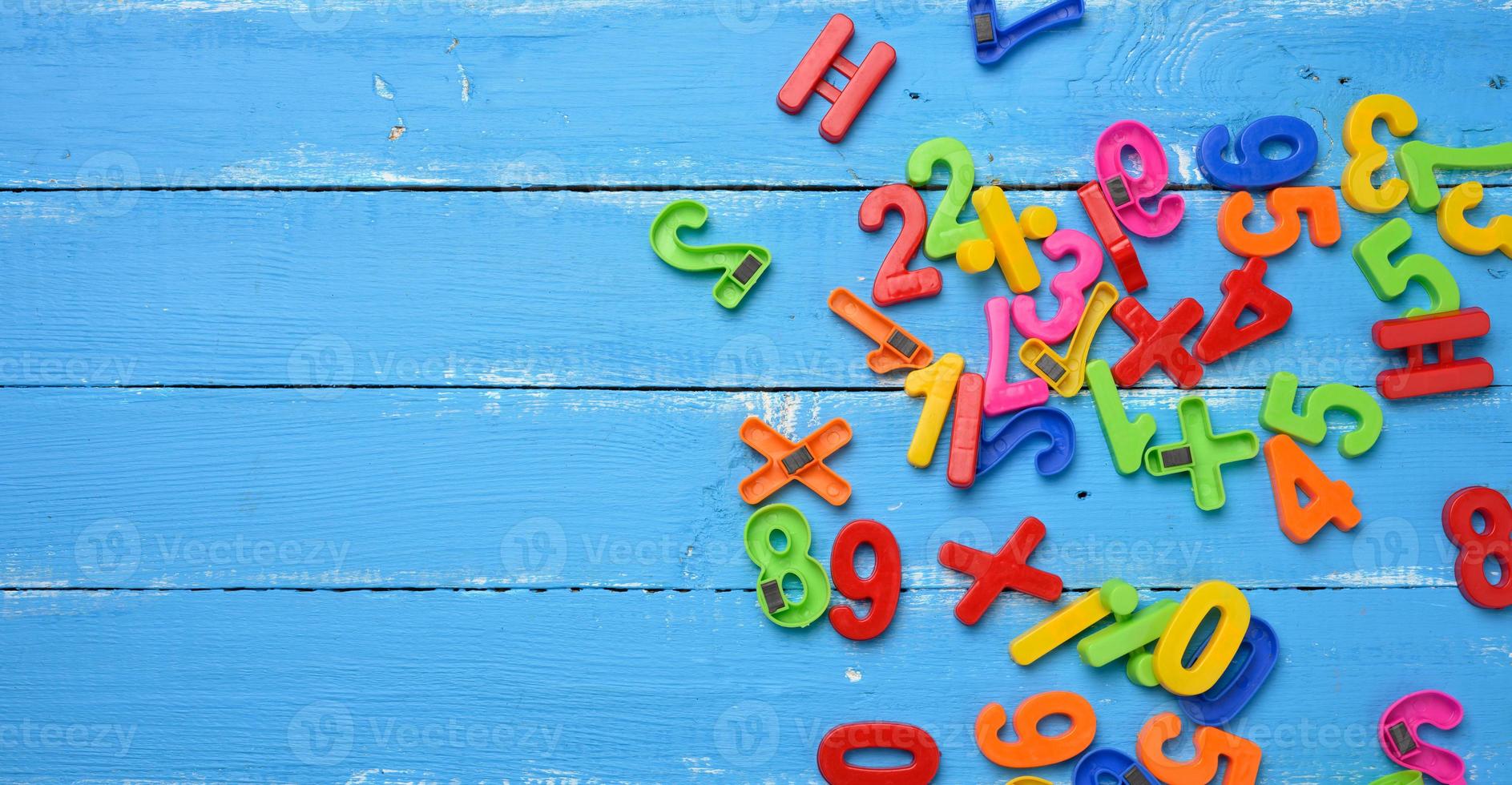 plastic numbers with magnet scattered on blue wooden background, top view photo