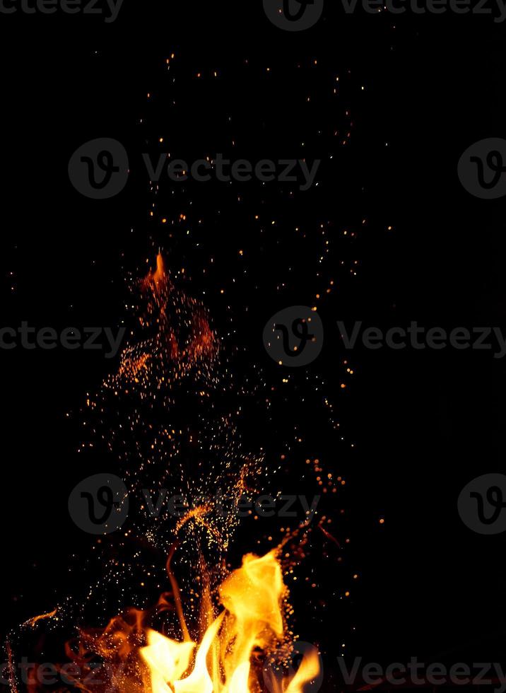 large burning bonfire with flame and orange sparks that fly in different directions photo