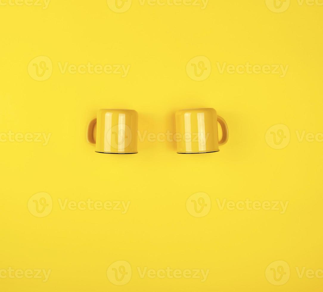 dos tazas de cerámica amarillas con un asa sobre un fondo amarillo foto