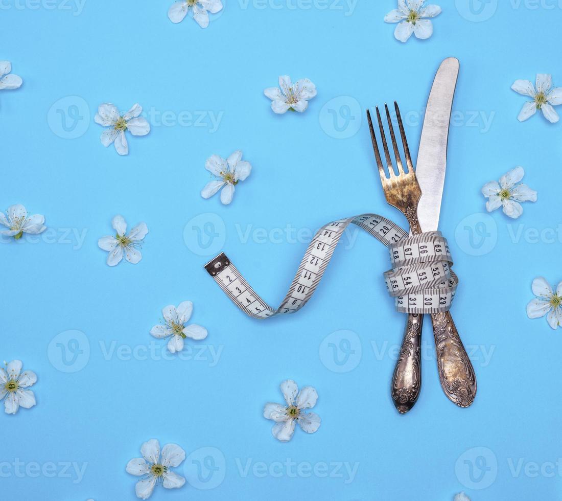 tenedor y cuchillo de hierro envueltos en una cinta métrica foto