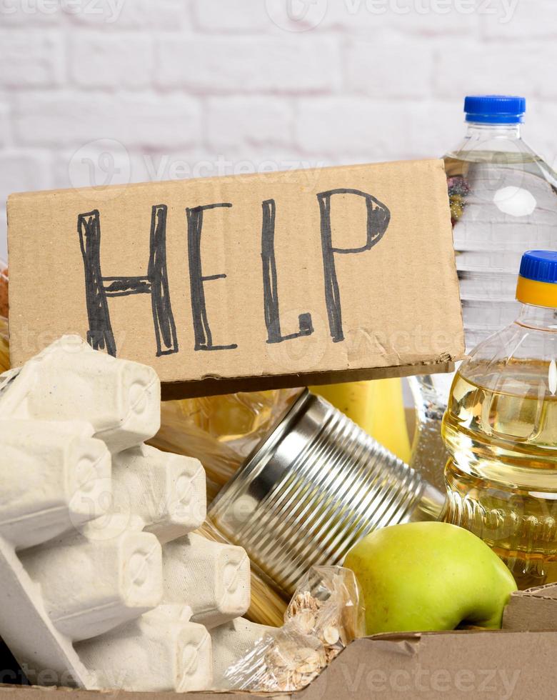 cardboard box with various products, fruits, pasta, sunflower oil in a plastic bottle and preservation photo