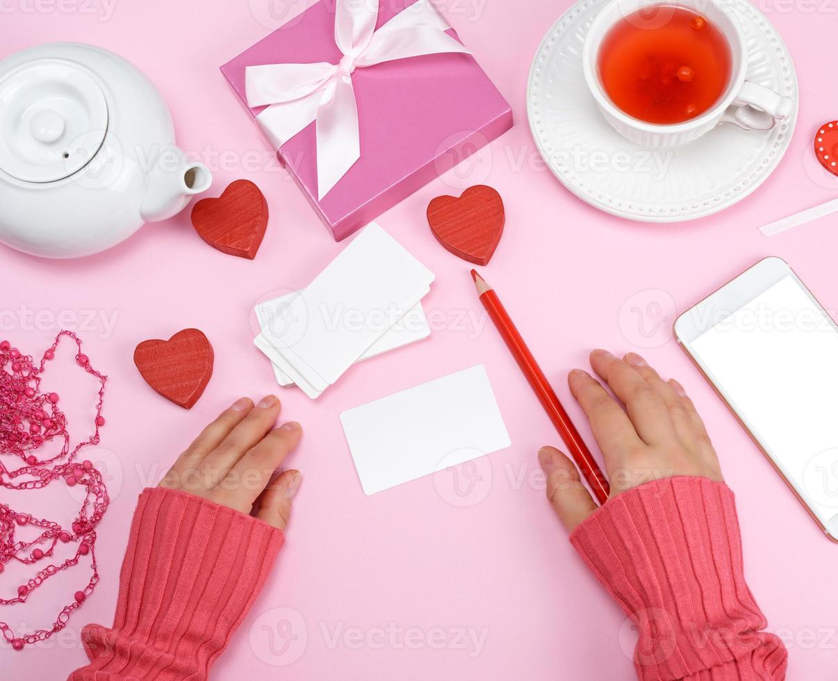 empty paper business cards and a red pencil, next to two women's hands photo