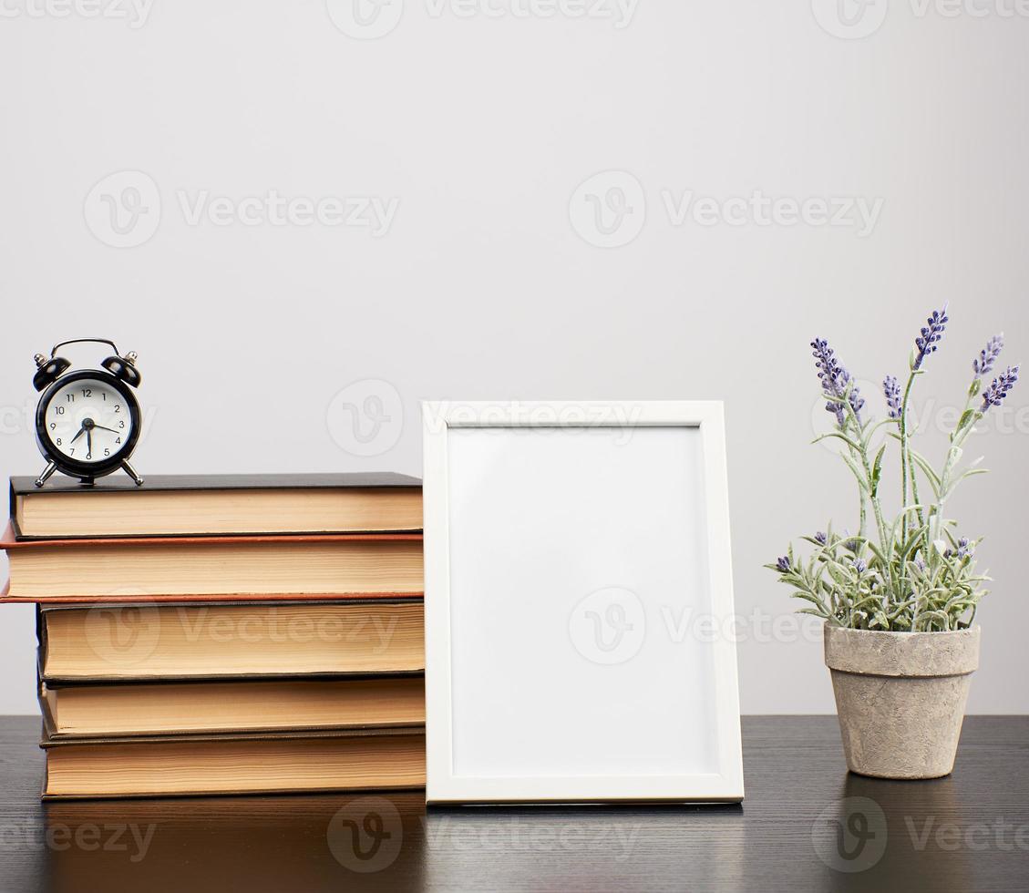 empty white photo frame, stack of books and a pot of growing lavender