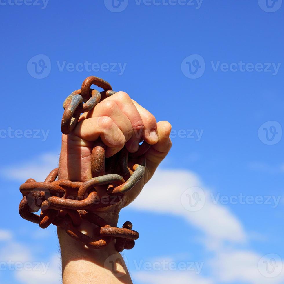 Man's hand is chained in iron chains photo