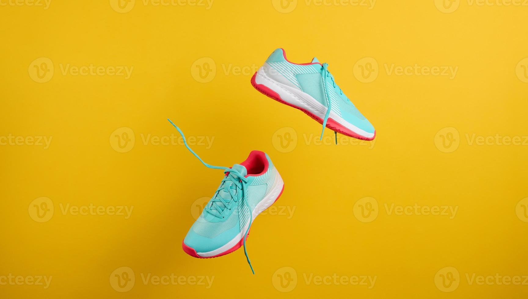 pair of textile blue sneakers with laces levitate on a yellow background. Shoes for sports, jogging photo