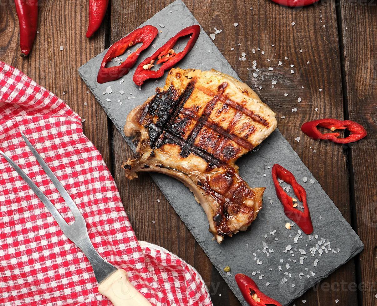 piece of fried pork tenderloin on a bone lies on a black board photo