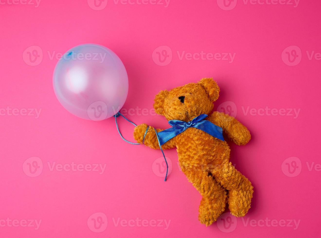 little brown teddy bear holding a blue inflated balloon photo