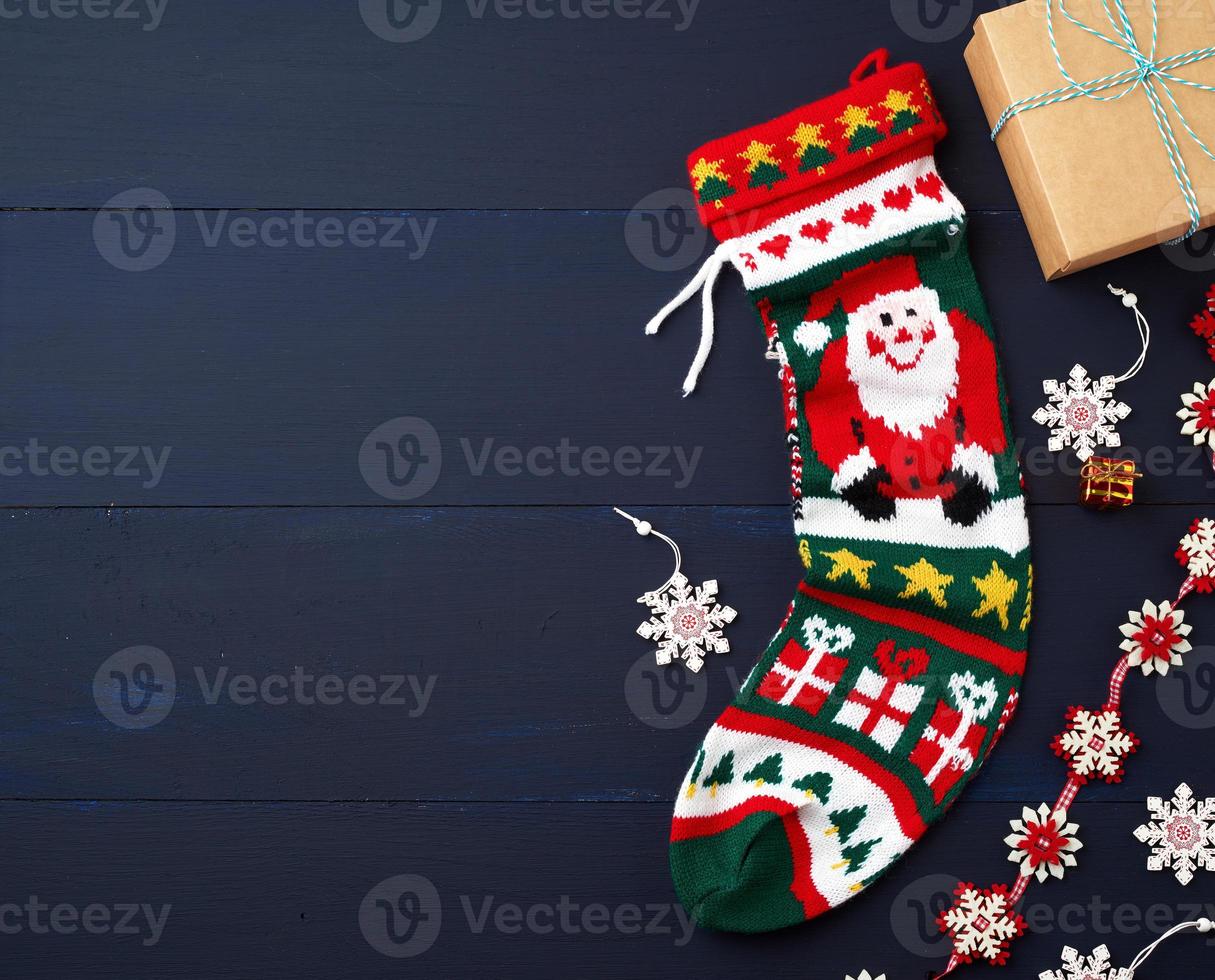 bright knitted christmas sock and decor on a blue wooden background photo