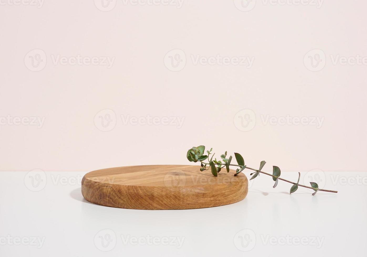 stage for displaying products, cosmetics with a round wooden podium and a green eucalyptus leaf photo