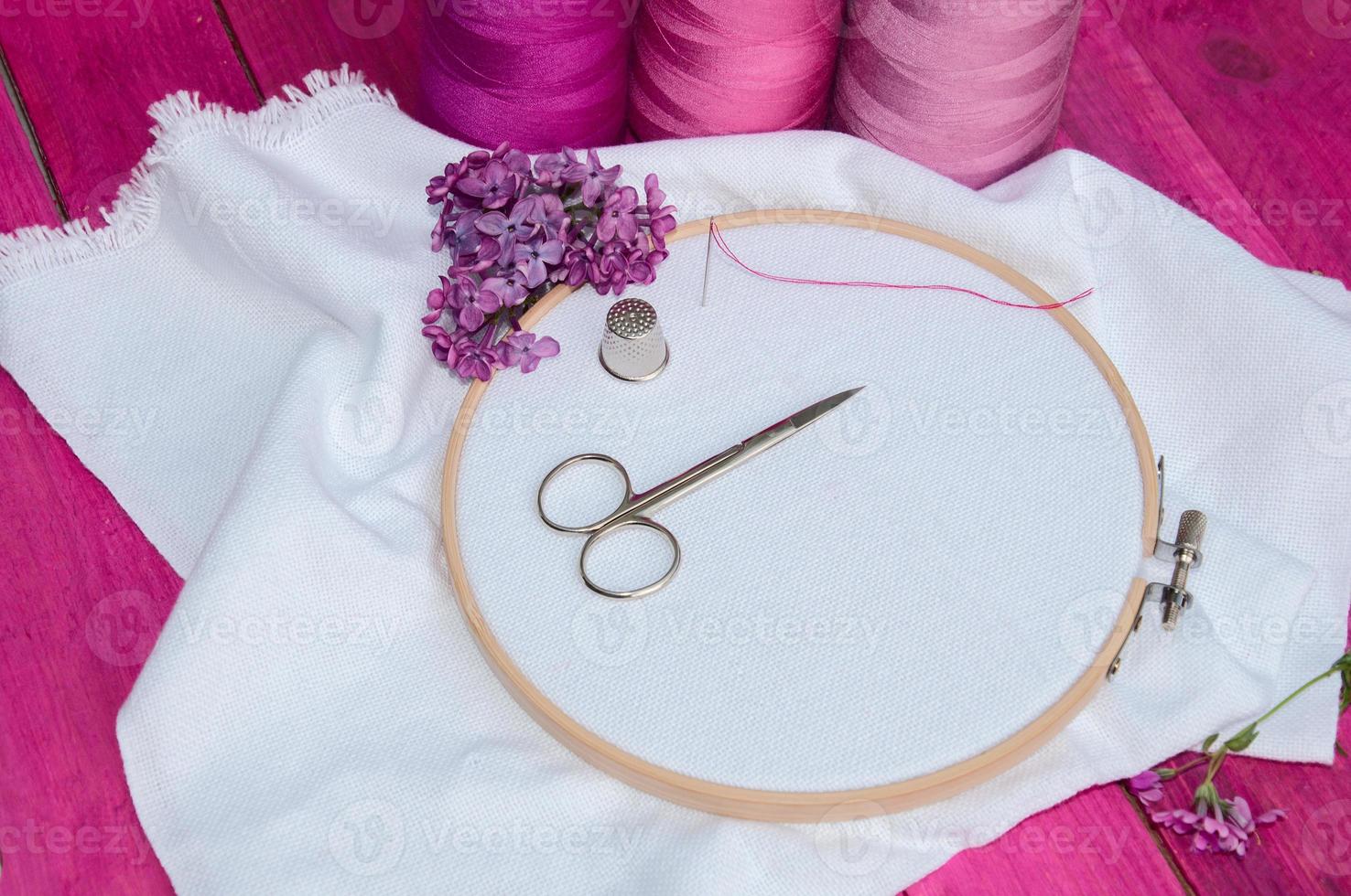 Pink thread and white fabric in the wooden embroidery frame for needlework photo