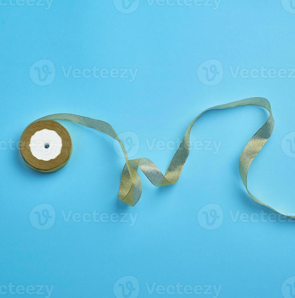Shiny golden satin ribbon on a blue background. Beautiful banner for celebration design photo