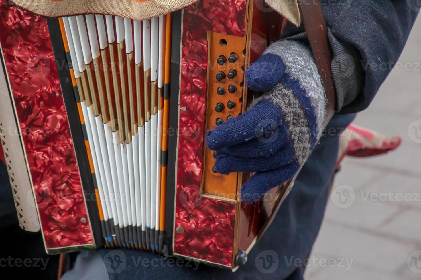 Close-up of a man's hand playing button accordion outdoors in winter. photo