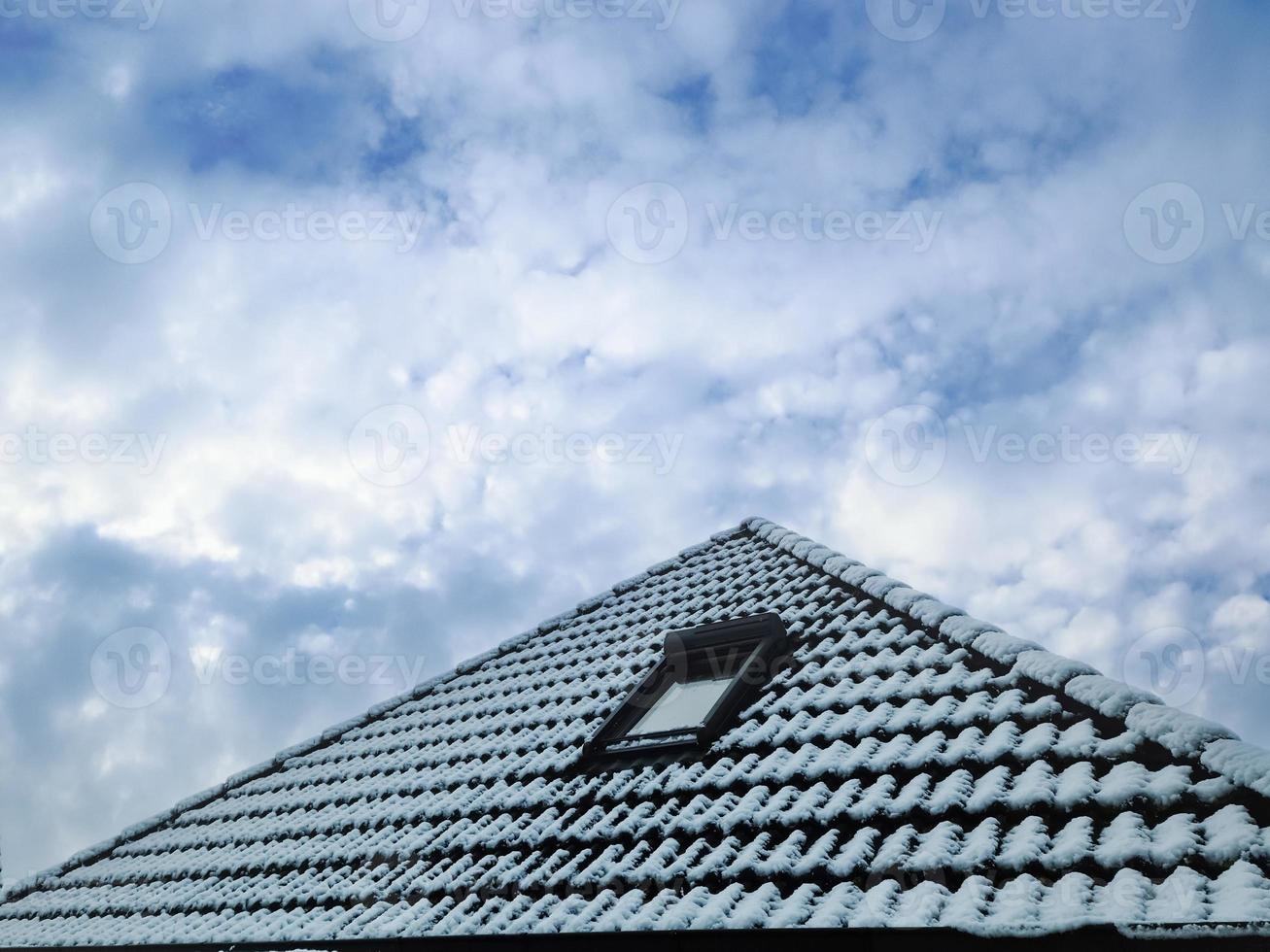 Open roof window in velux style with black roof tiles covered in white snow photo