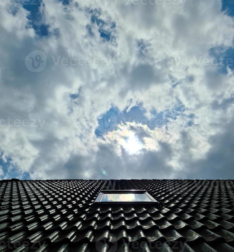 Open roof window in velux style with surrounding black roof tiles photo