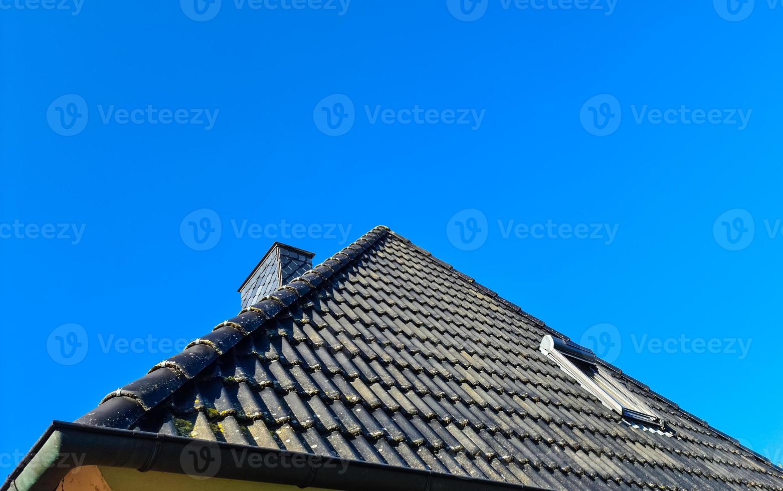 ventana de techo abierta en estilo velux con tejas negras. foto