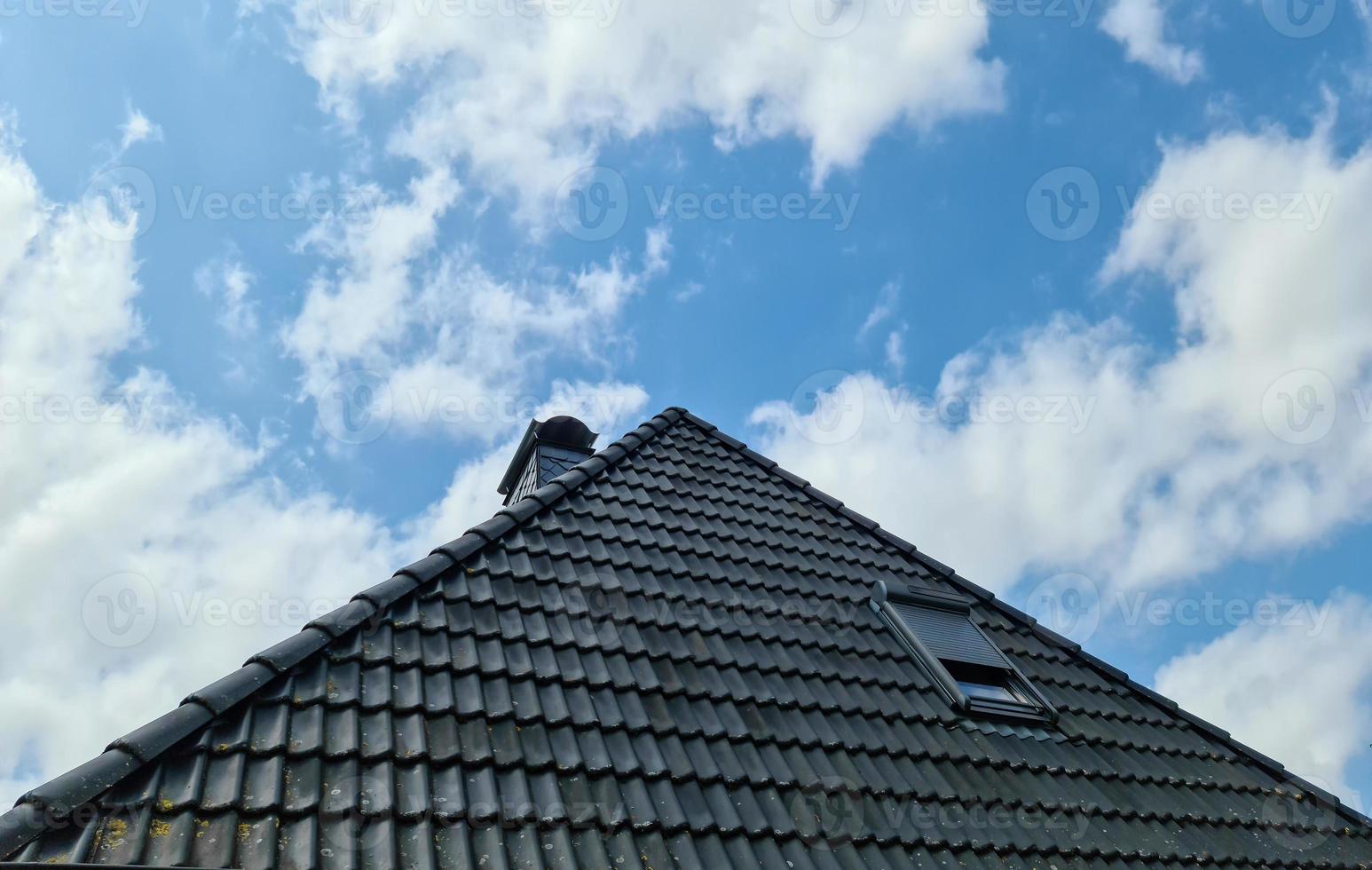 Open roof window in velux style with surrounding black roof tiles photo