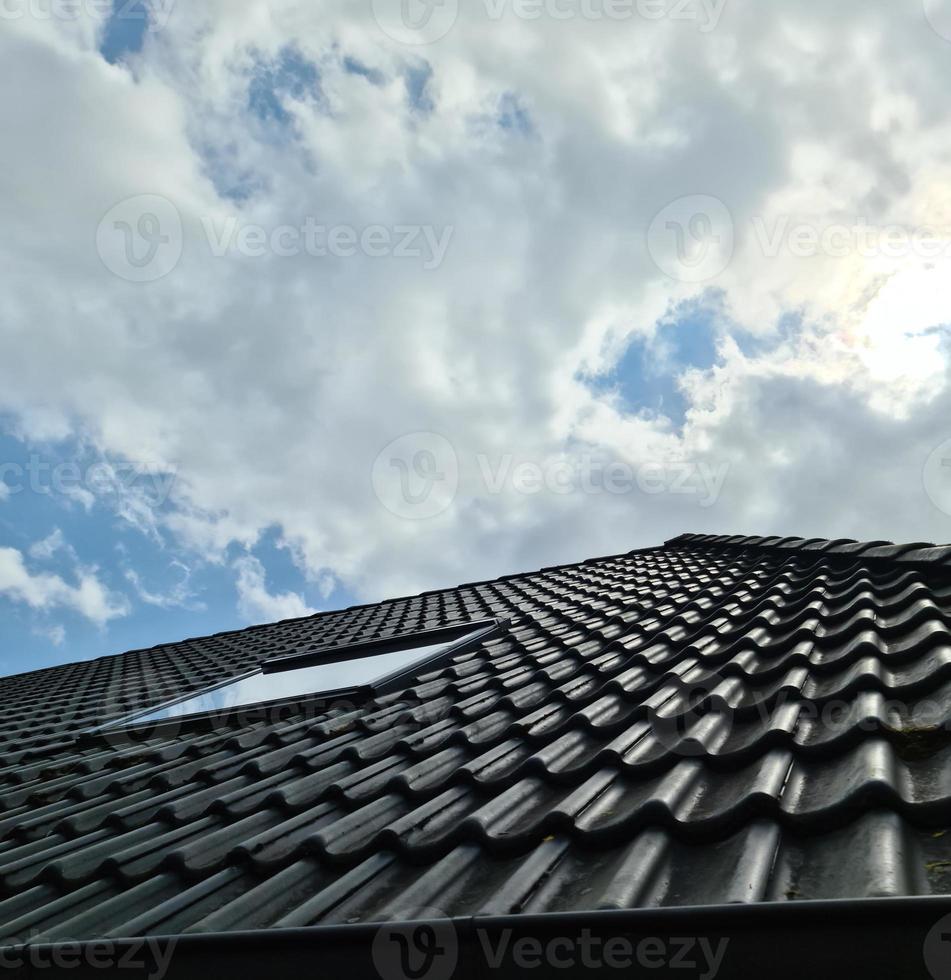 ventana de techo abierta en estilo velux con tejas negras circundantes foto