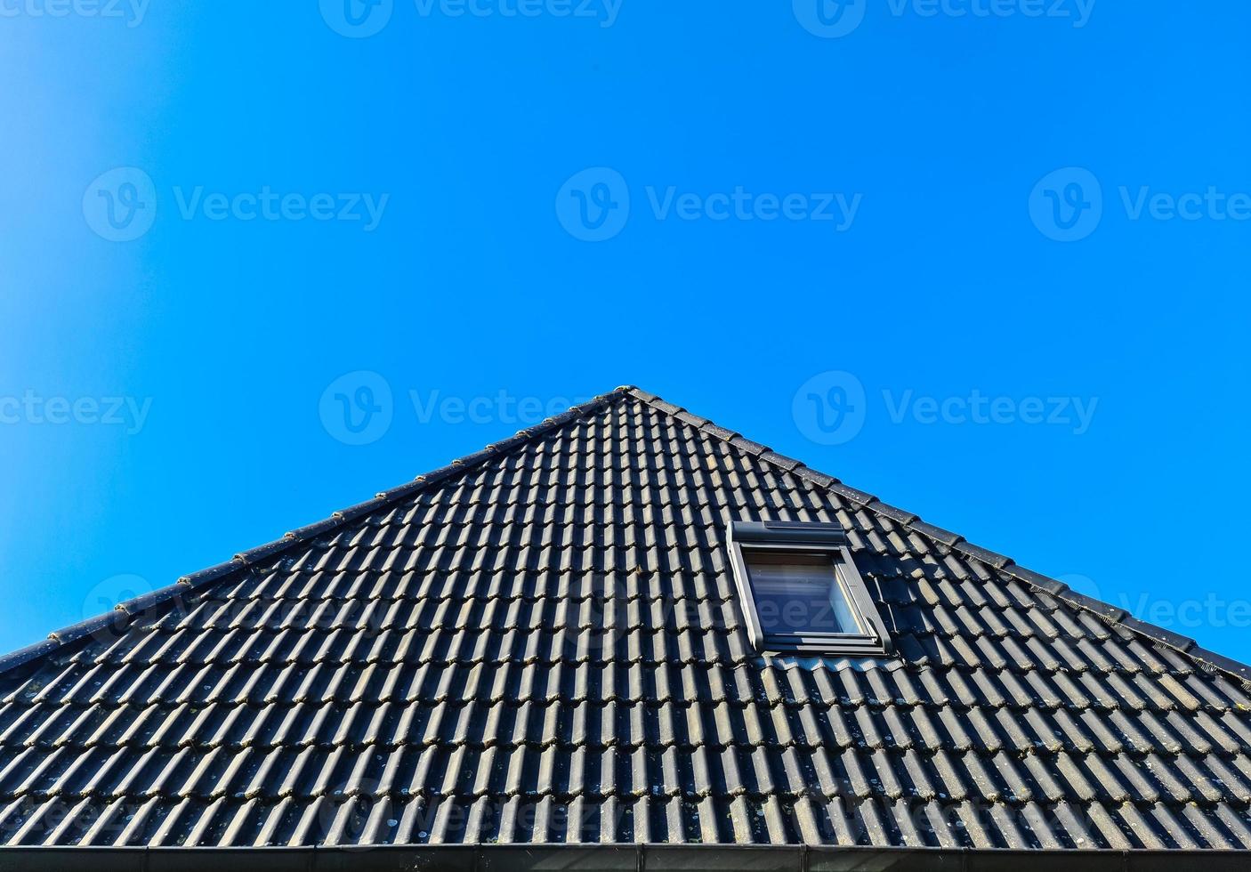 ventana de techo abierta en estilo velux con tejas negras. foto