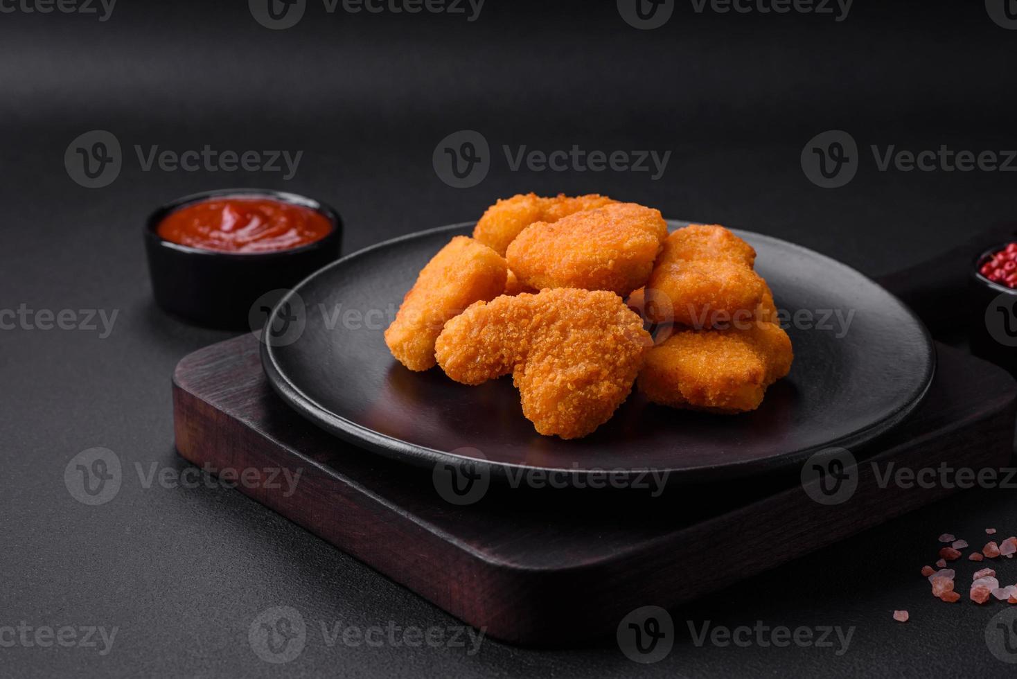 Delicious fresh crispy chicken nuggets on a dark concrete background photo
