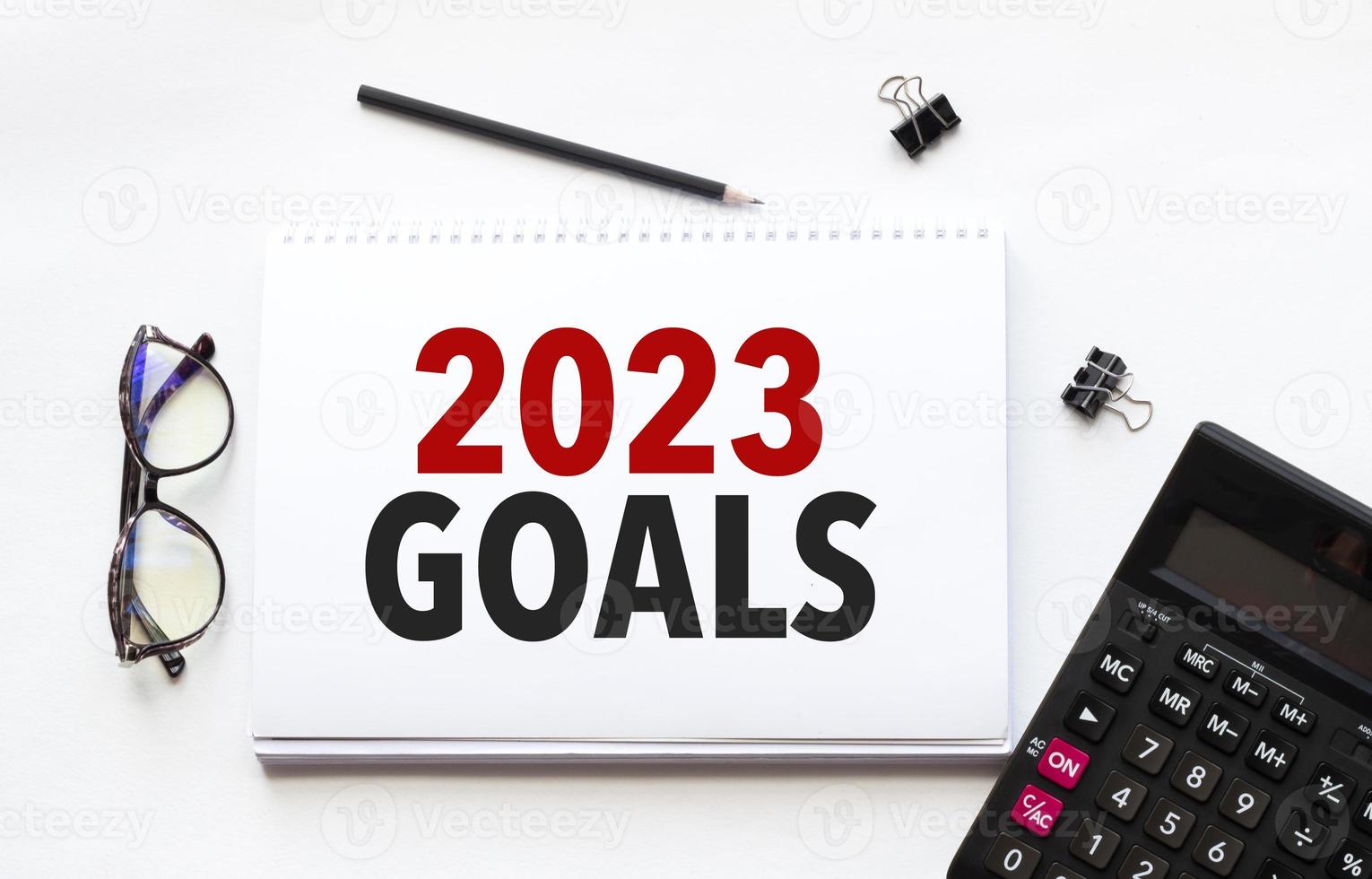 Business concept. Notebook with text goals 2023 sheet of white paper for notes, calculator, glasses, pencil, pen, in the white background photo