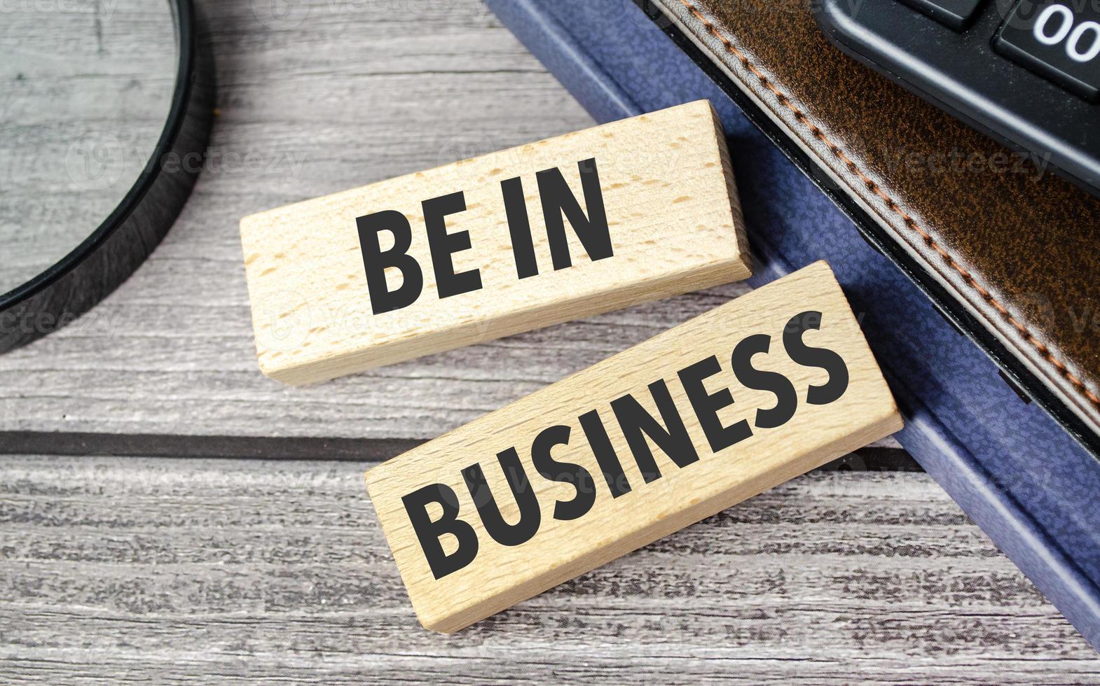 be in business. text on wooden blocks on wooden background with office supplies photo