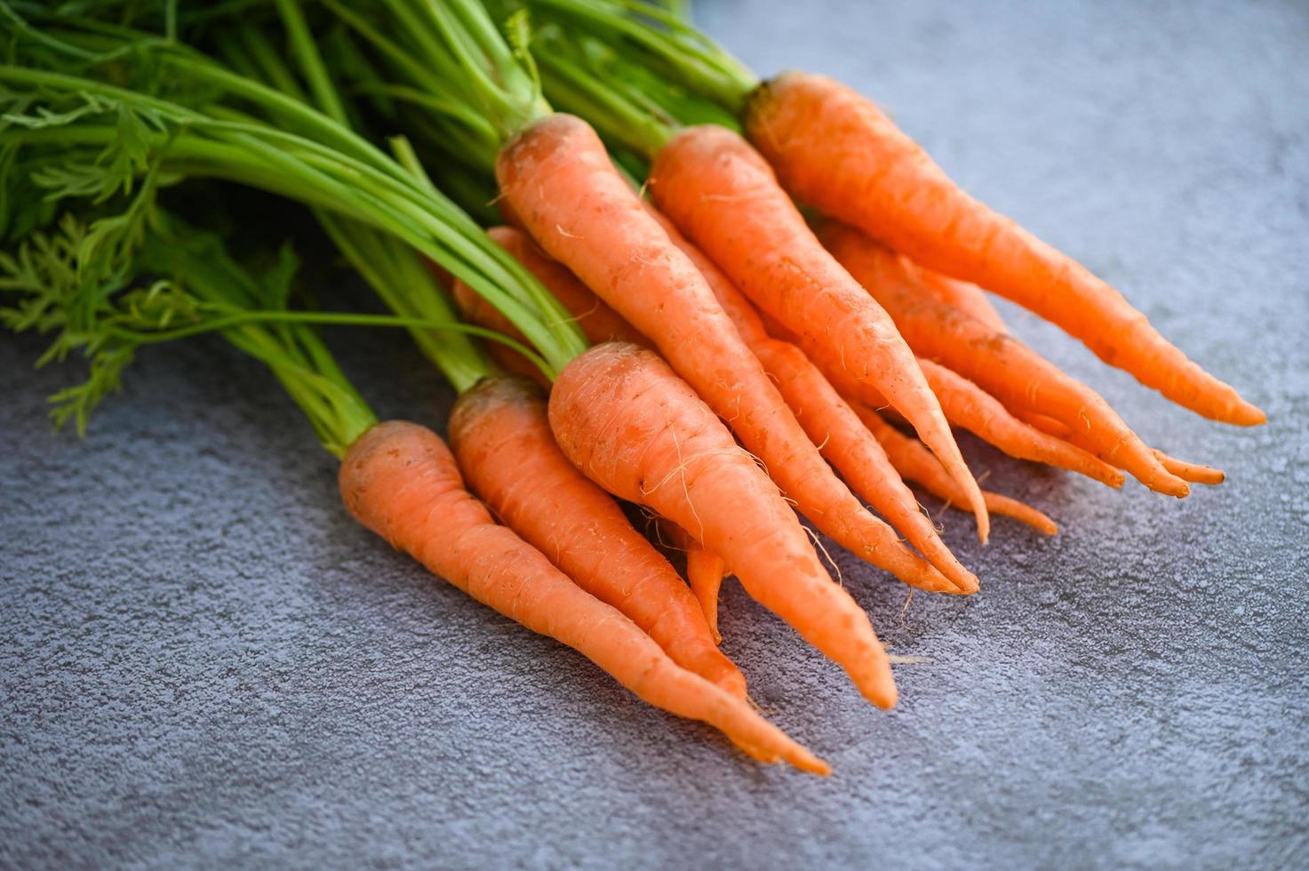 zanahoria en el fondo de la mesa, zanahorias frescas y dulces para cocinar frutas y verduras para el concepto de salud, manojo de zanahorias para bebés y hojas foto