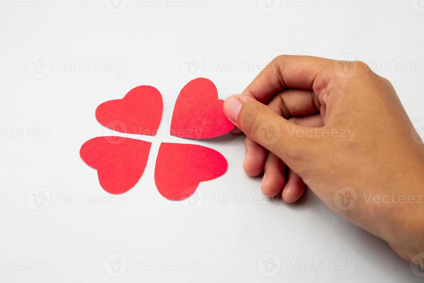 Hand completing heart puzzle forming clover photo