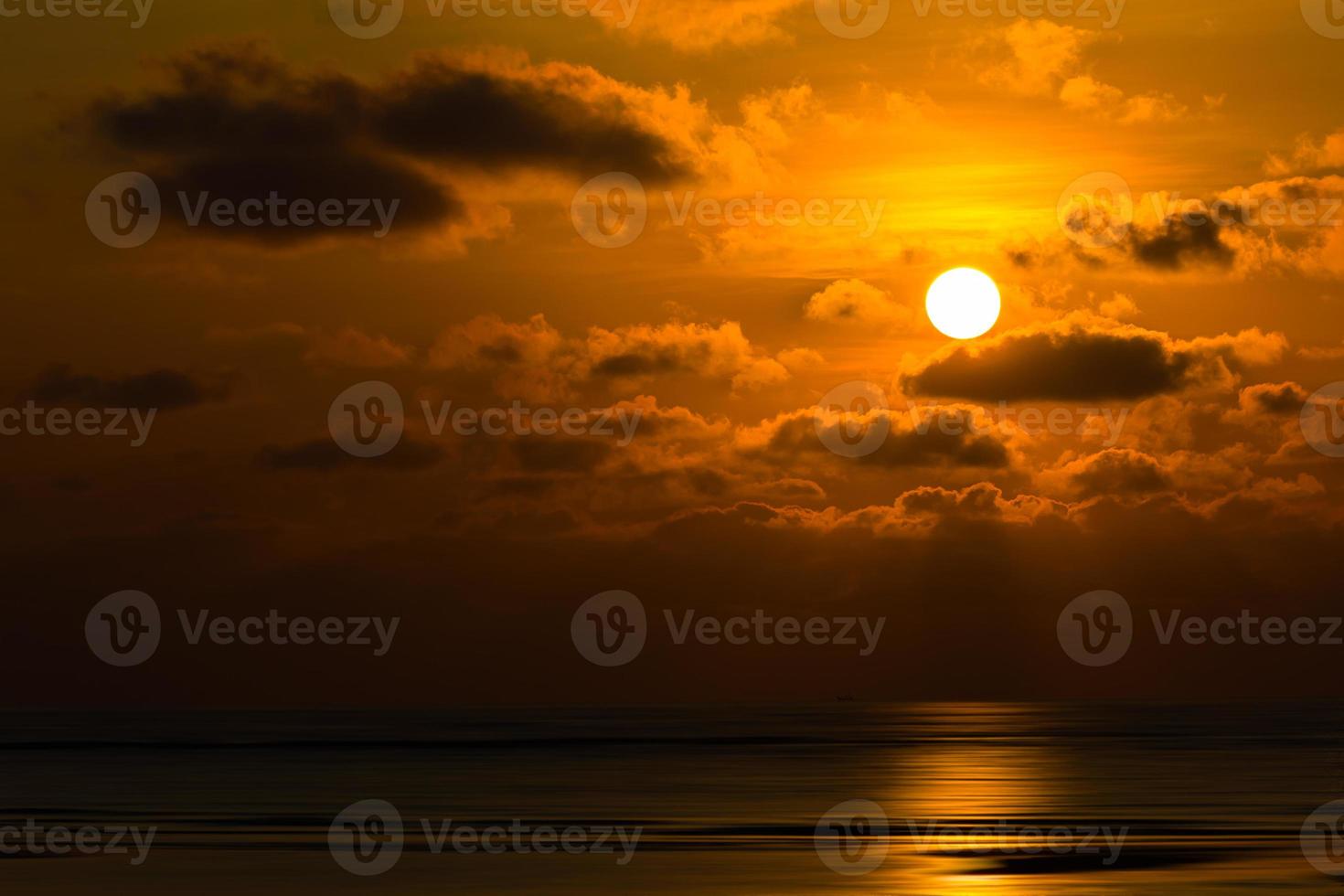 Dramatic sunset behind clouds above the sea photo