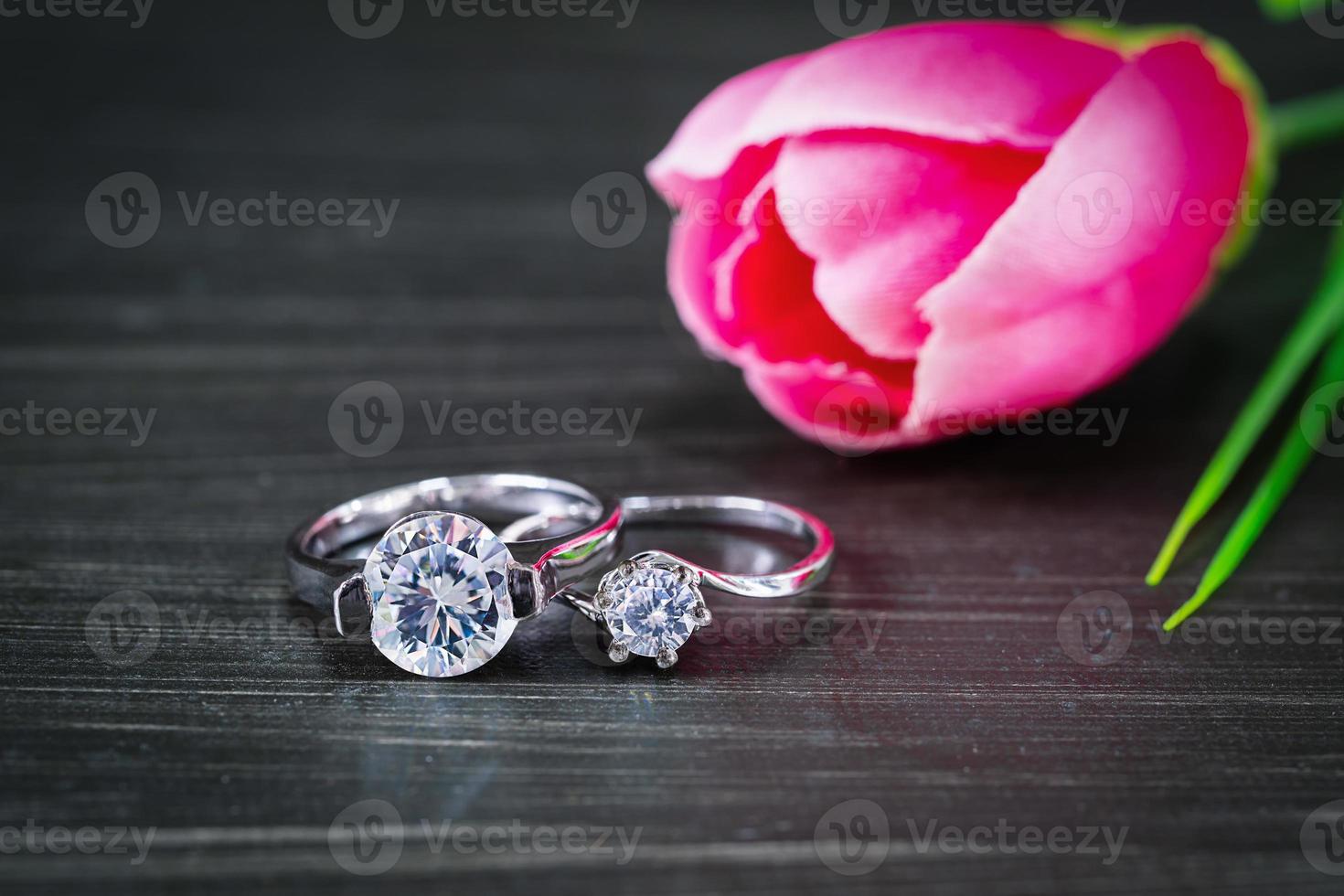 Diamond wedding rings with tulip flower on black background photo