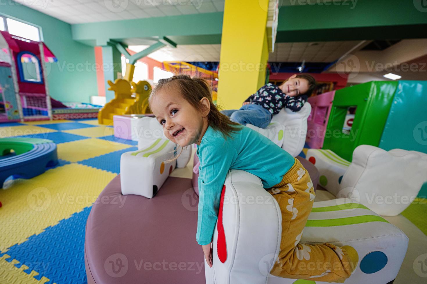 Happy sisters playing at indoor play center playground. photo