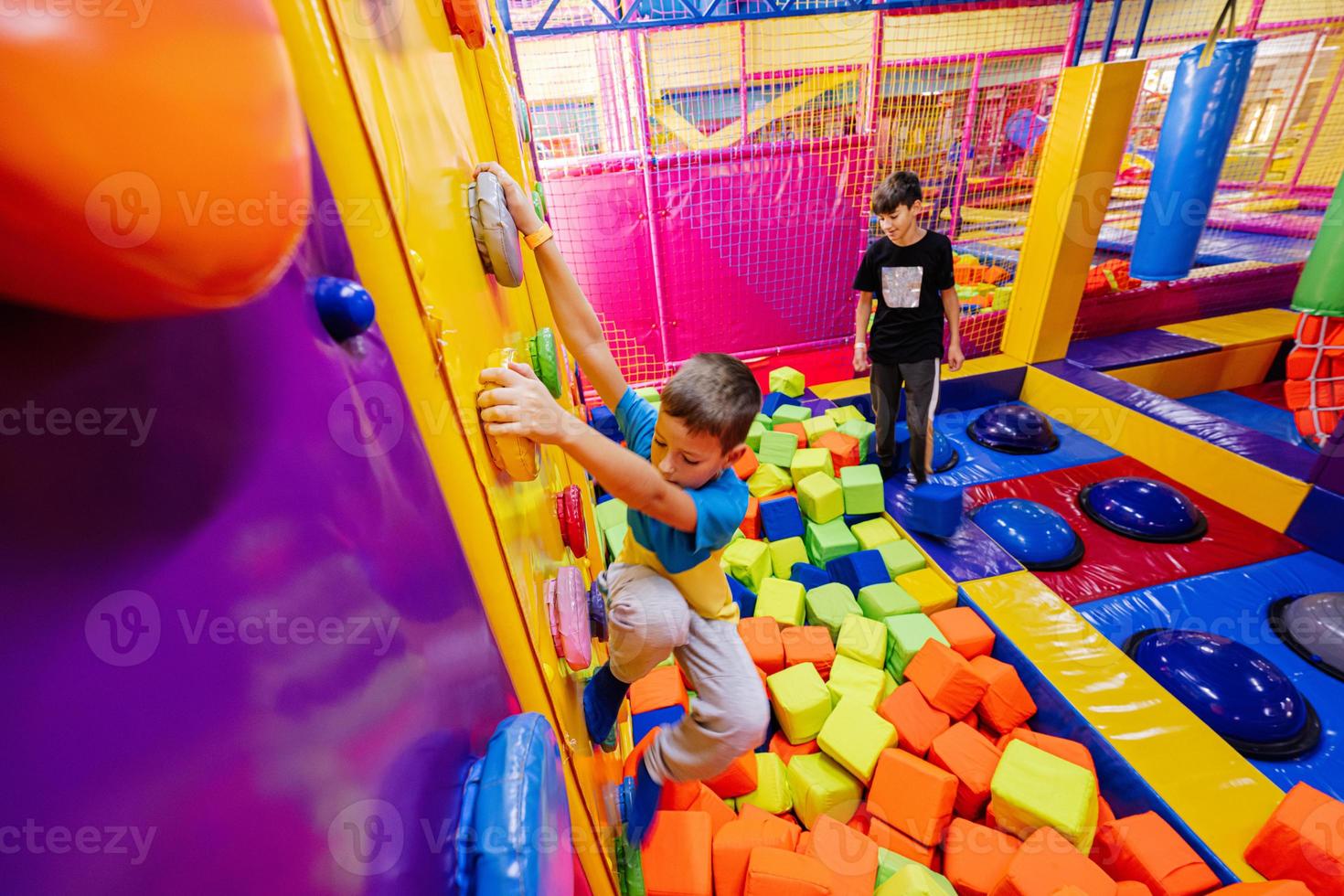 Happy kids playing at indoor play center playground,  brothers climbs in wall. photo