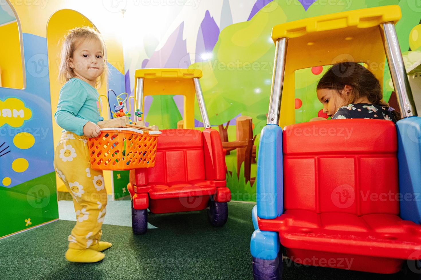 Sisters playing at indoor play center playground , girl in toy car. photo