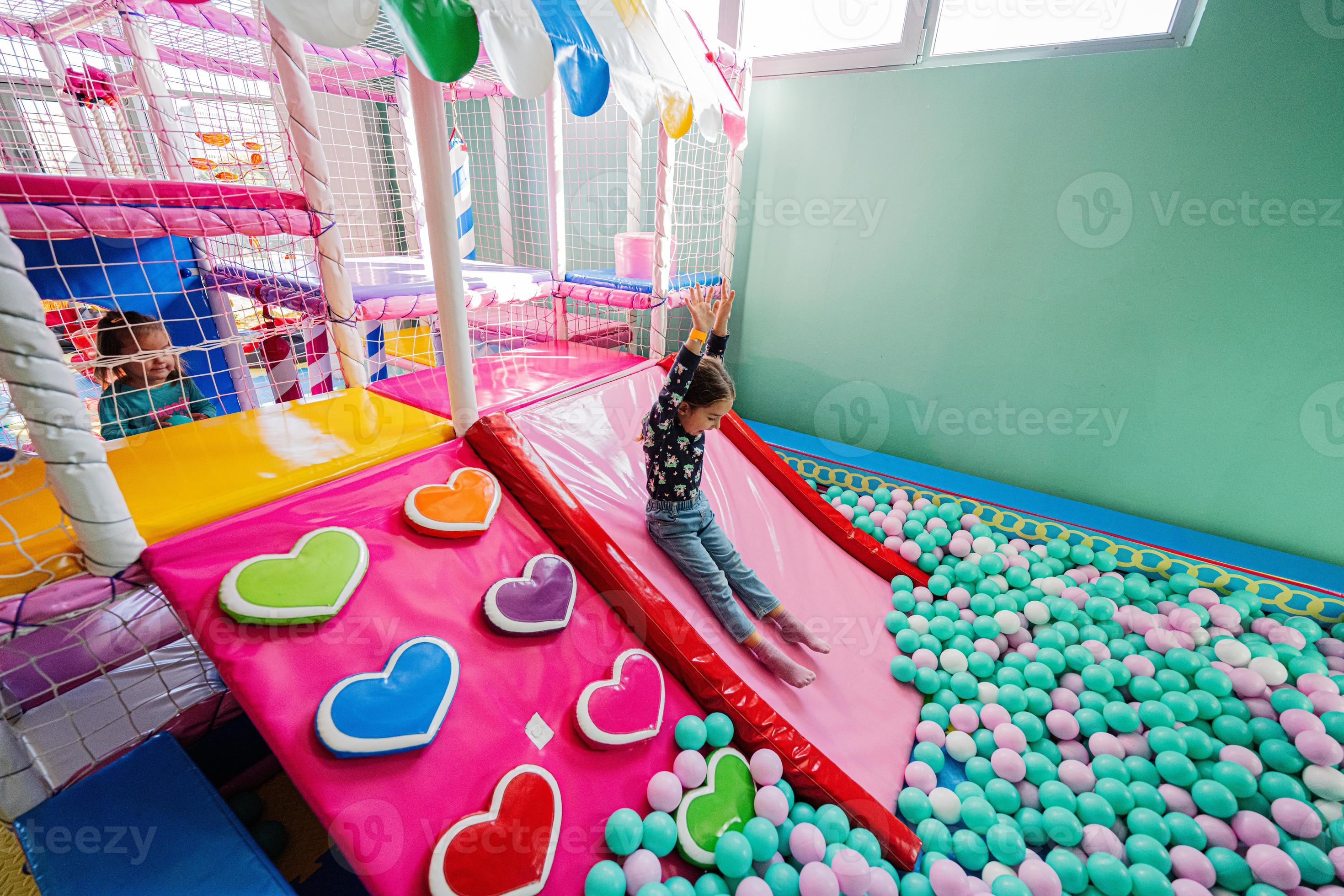 Happy girl playing at indoor play center playground. Sliding in color