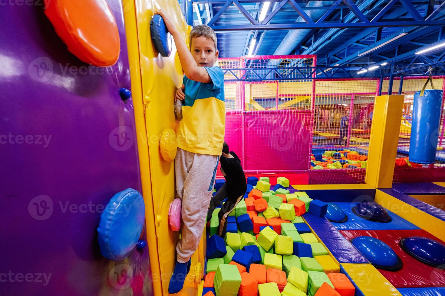 Happy kids playing at indoor play center playground,  brothers climbs in wall. photo