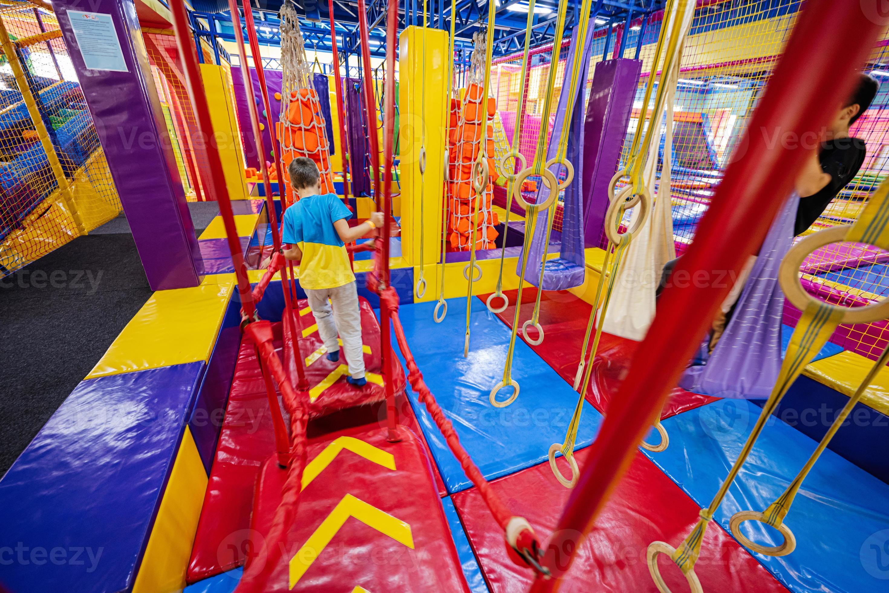 Happy kids playing at indoor play center playground, boy climbs the