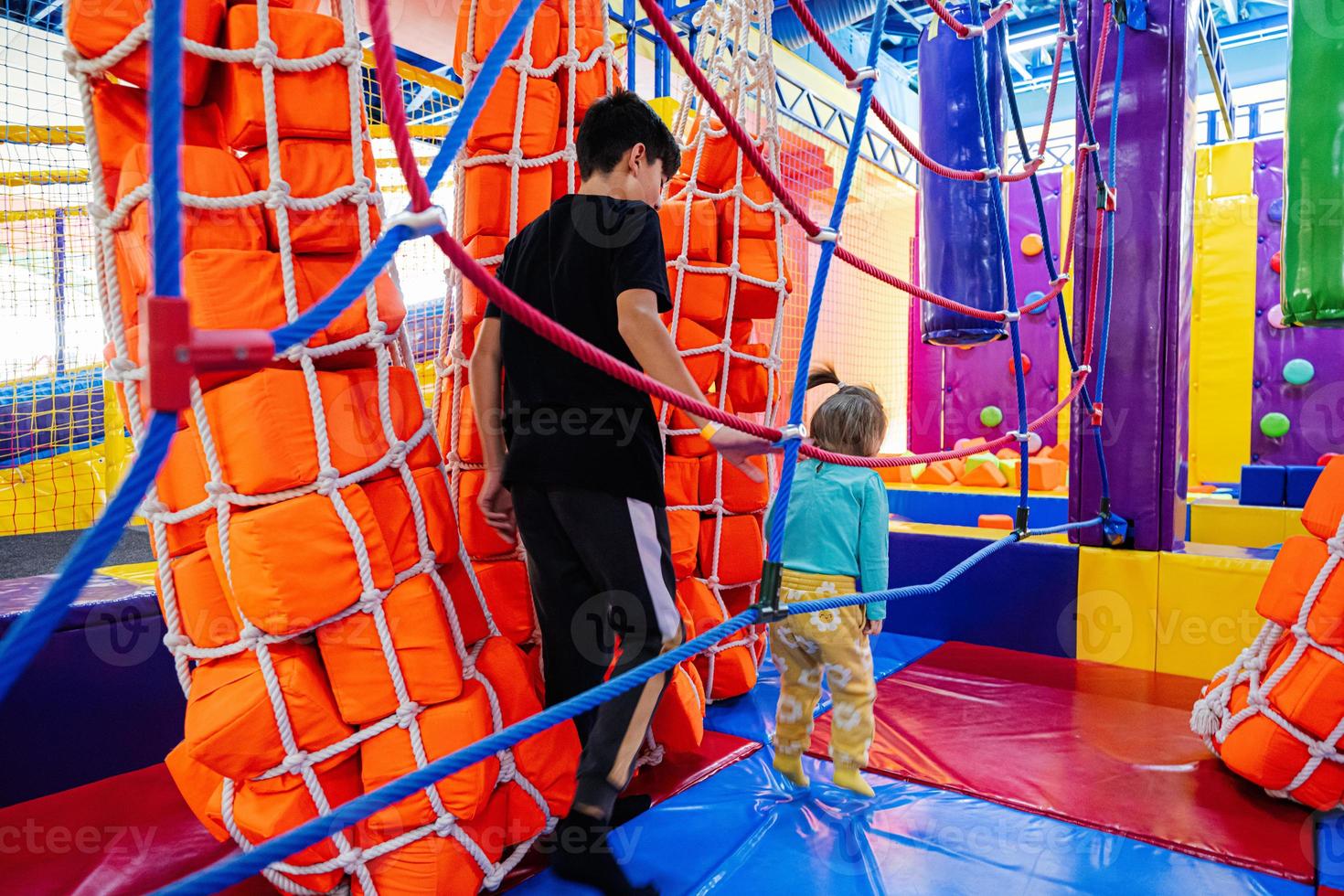 Brother with sister playing at indoor play center playground. photo