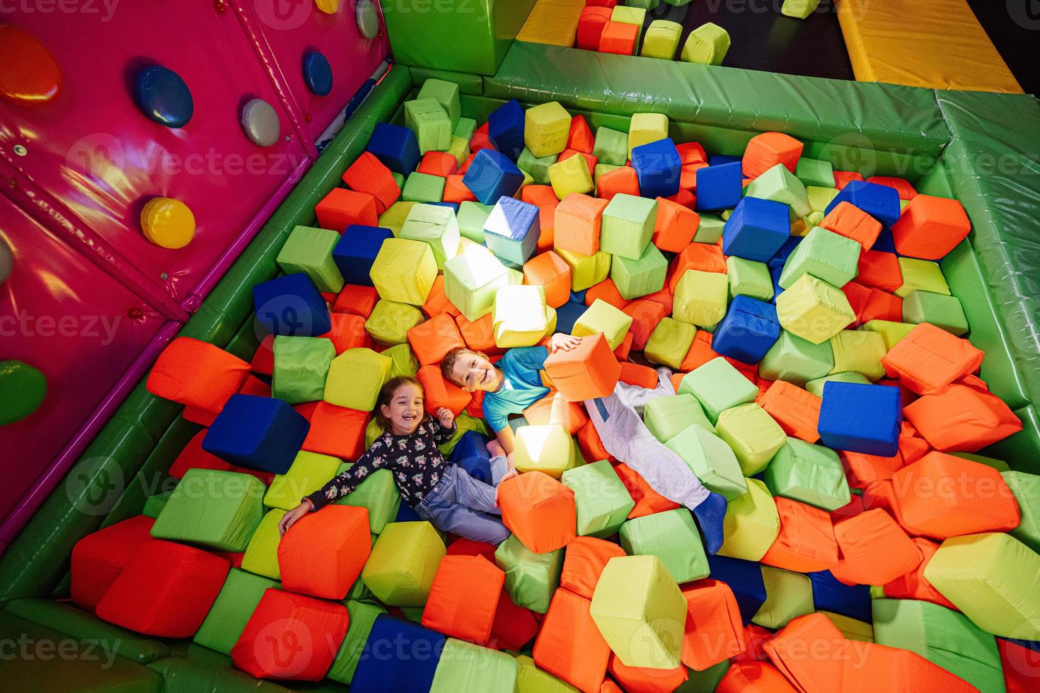Brother with sister playing at indoor play center playground in color cubes pool. photo