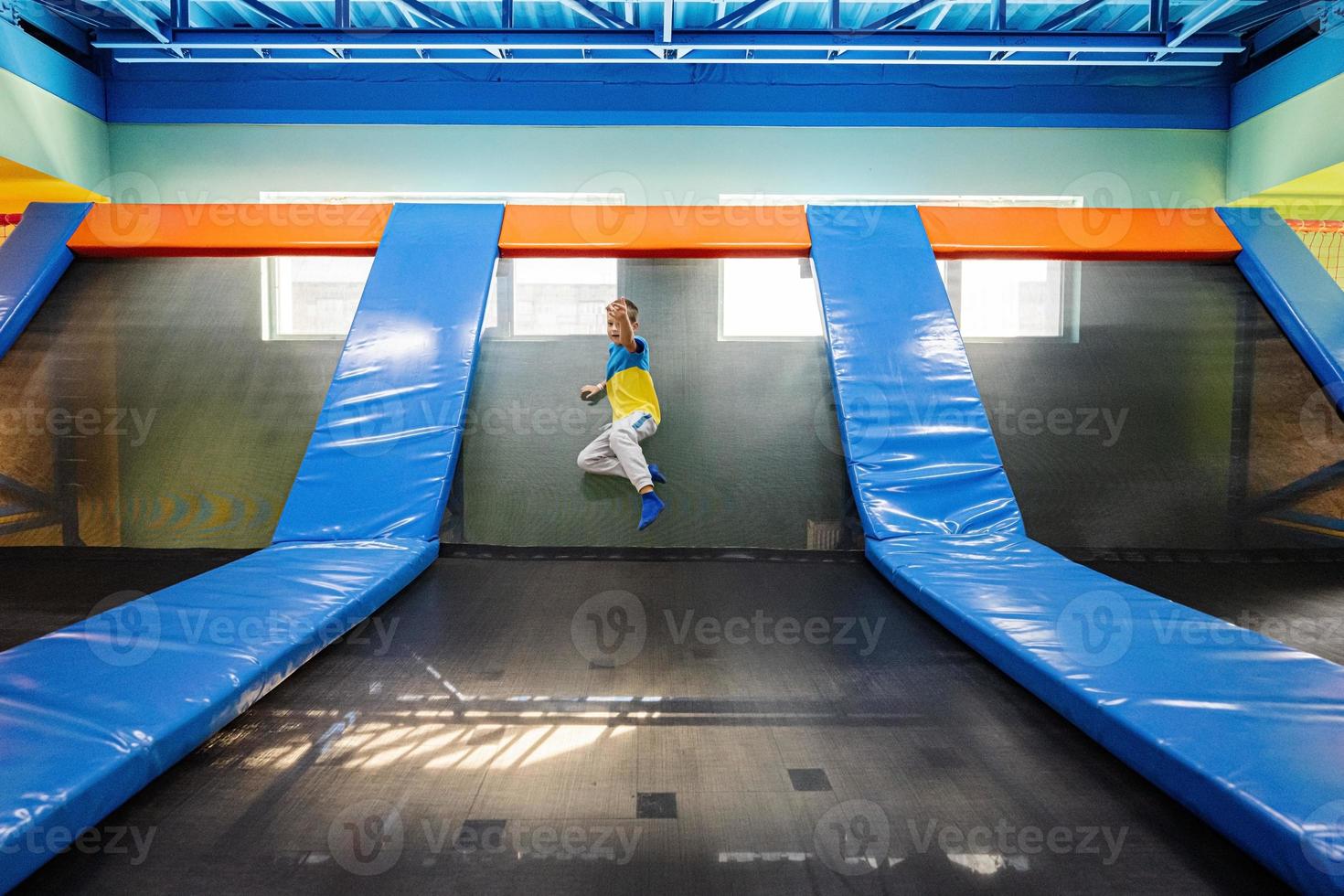 Boy playing at indoor play center playground , jumping in trampoline. photo