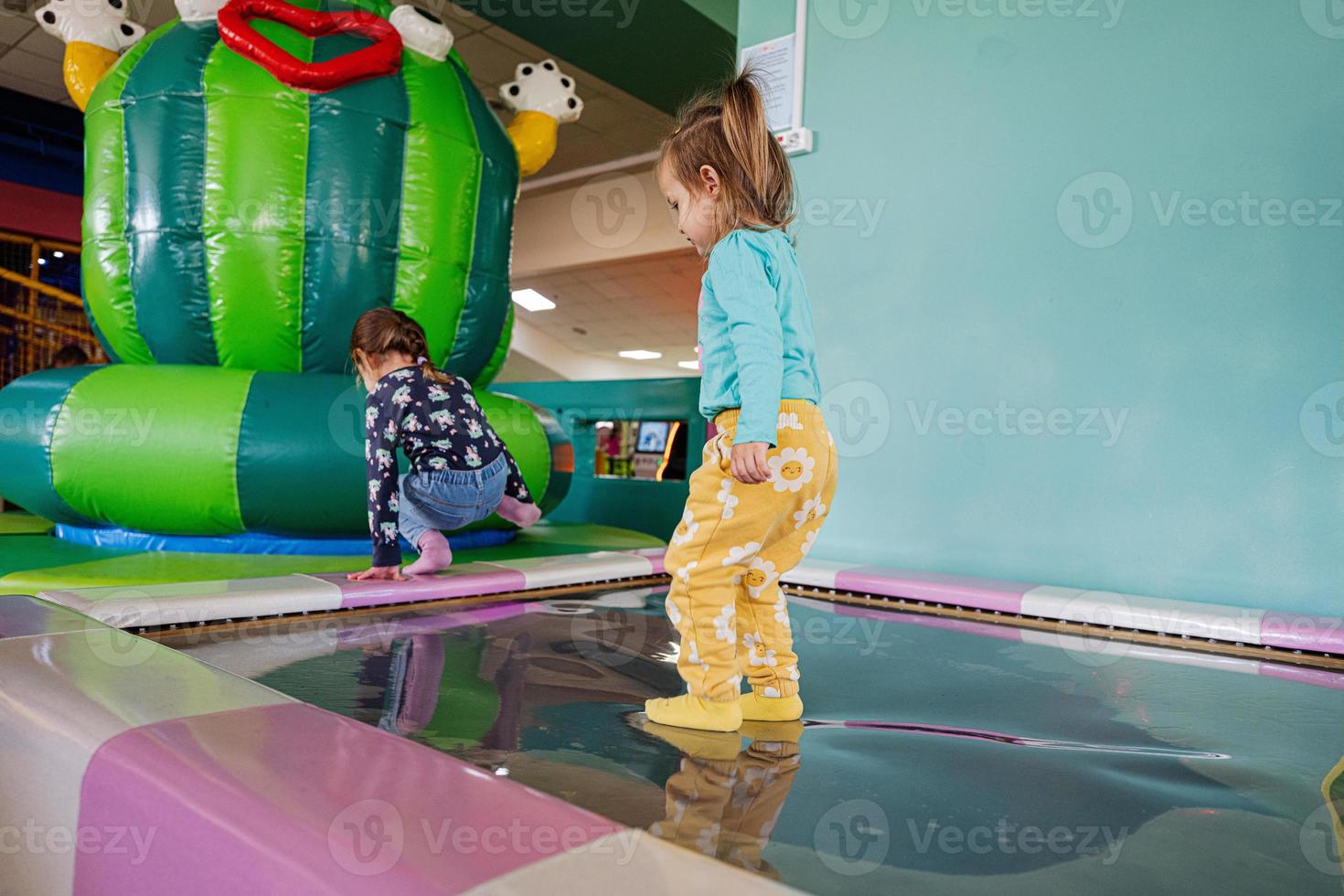 Happy sisters playing at indoor play center playground in water trampoline. photo