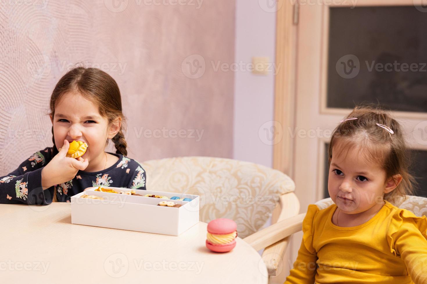 Two sister eat delicious tasty sweet color macarons. photo