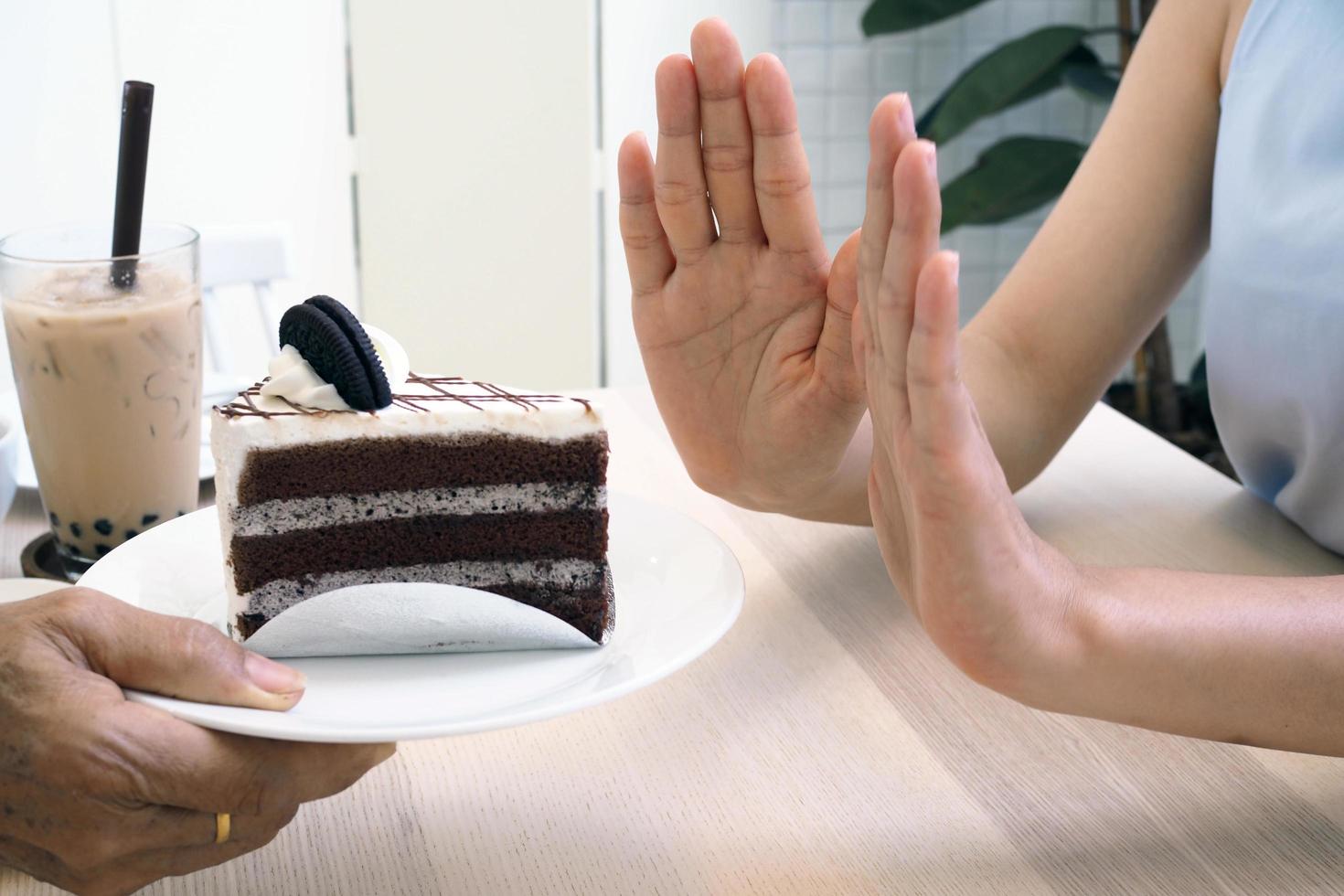 las mujeres empujan el plato de la torta y el té con leche de perla. Deja de comer postre para adelgazar. foto