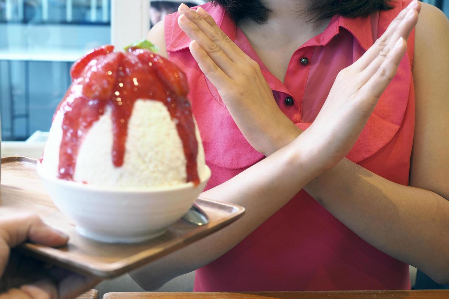 las mujeres empujan la copa de helado. se negaba a comer todo tipo de dulces. evitar el azúcar y los dulces para una buena salud. concepto de dieta foto