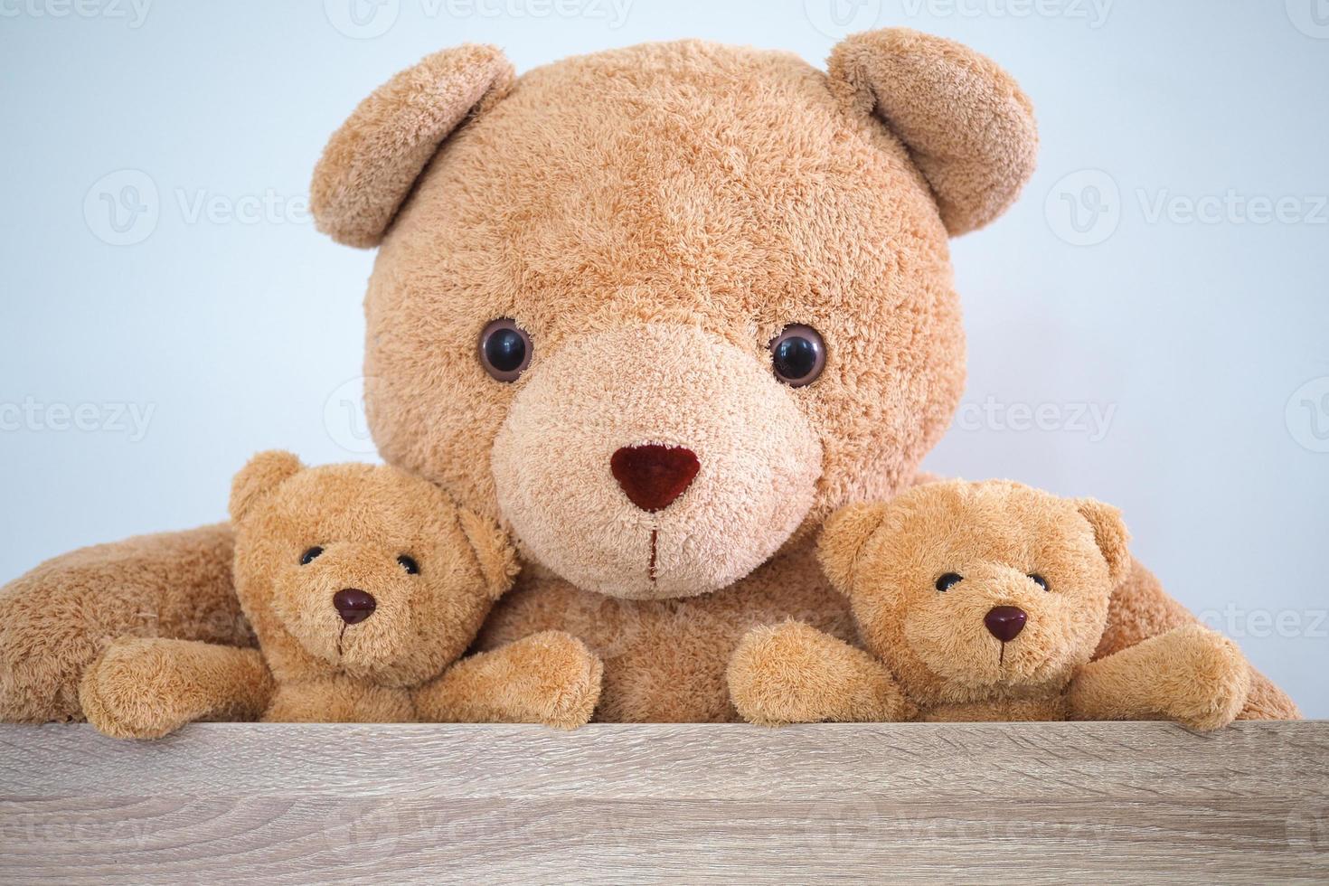 Brown teddy bear family sitting together in a chair in the room. photo